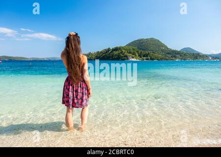 A woman wades in shallow clear water at Nidri Beach, Lefkada, Ionian Islands Greece