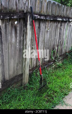 Rake Leaning Against a Wooden Fence in Kansas Stock Photo