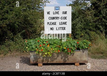 Please leave no litter  - we love our countryside notice with NHS logo mounted in layby in old drinking trough full of flowers near Stratford upon Avo Stock Photo