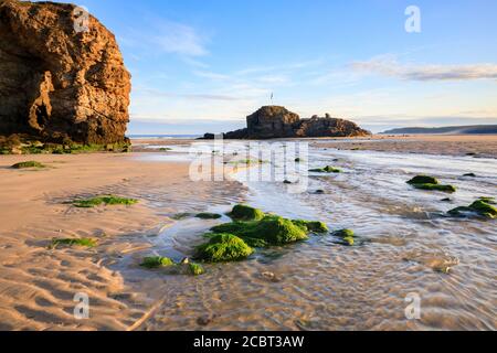 The natural sea arch and Chapel Rock on Perranporth Beach in Cornwall captured on a morning in mid-July with sand patterns as foreground interest. Stock Photo