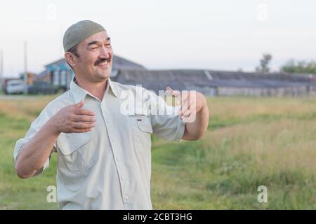 Muslim senior man stands and smiles on the background of the Siberian village, Russia Stock Photo