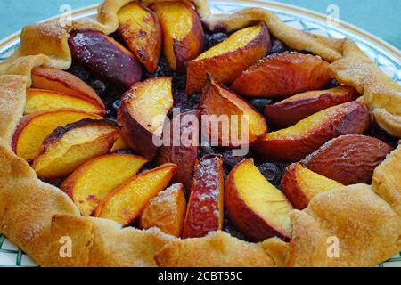 Homemade rustic galette pastry with fresh peaches and blueberries Stock Photo