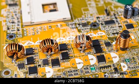 Four inductors with ferromagnetic core on circuit board of computer mainboard. Electrical components. Toroidal and cylindrical induction coils. Tech. Stock Photo