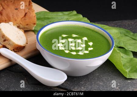 spinach cream soup in a bowl with fresh bread and cream Stock Photo