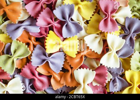 Colorful farfalle pasta background. Raw organic farfalle. Traditional Italian farfalle pasta. Italian Cuisine. Bow tie noodles. Uncooked dried farfall Stock Photo