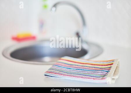 Kitchen towel and sink without dirty dishes background. Dishcloth on kitchen countertop. Cleaning and dish washing concept. Stock Photo