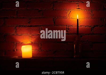 Candle lights on loft wall background. Yellow and red fire in wax candles. Romantic atmosphere. Red brick wall in candlelight Stock Photo