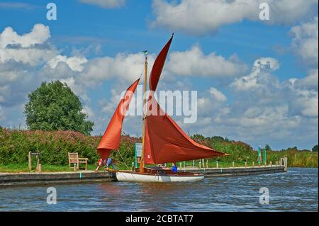 Brown sailed boat at Ludham Staithe on the River Ant, Norfolk Broads National Park on a blustery August day Stock Photo