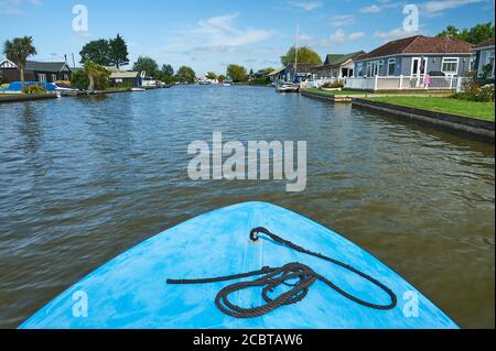 River Thurne riverbank lined with quirky collection of huts and summer houses on the approach to Potter Heigham, Norfolk Stock Photo