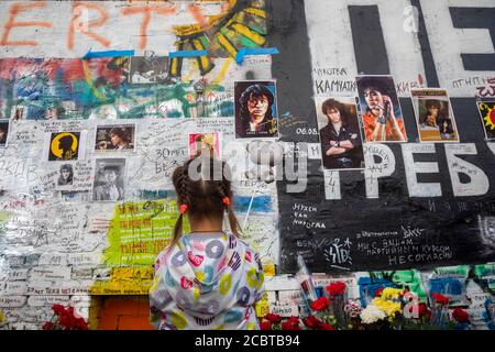 Moscow, Russia. 15th of August, 2020 A little girl looks on Viktor Tsoi's rock singer portraits on the Tsoi Wall on Arbat street in Moscow on the 30th anniversary of the singer's death, Russia. The Tsoi Wall is a graffiti-covered wall in Moscow, dedicated to musician Viktor Tsoi and his band Kino Stock Photo