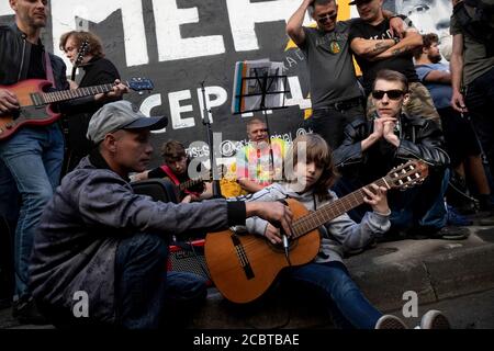 Moscow, Russia. 15th of August, 2020 A little fan of Viktor Tsoi sings a song with a guitar on the background of the Tsoi Wall on Arbat street in Moscow on the 30th anniversary of the death of the singer, Russia. The Tsoi Wall is a graffiti-covered wall in Moscow, dedicated to musician Viktor Tsoi and his band Kino Stock Photo