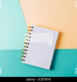 Open notebook with blank sheet and golden spiral on a colorful pastel background. The concept of education, writing down ideas, plans. Place for text. Stock Photo