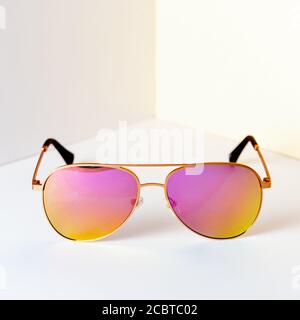 Modern pink aviator sunglasses in front of the corner of the wall background with copy space. Product photograph of minimalist concept with room for t Stock Photo