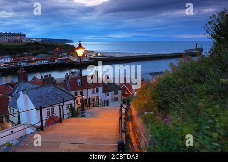 Image showing the 199 steps to whitby abbey after sunset with a street lamp and the harbour in the background. Whitby, North Yorkshire, England, UK. Stock Photo