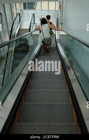 Looking down an escalator with 2 people ahead Stock Photo