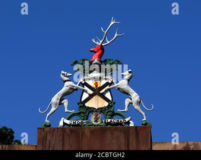 The crest of the clan Colquhoun sits above the gates at the former entrance to Rossdhu Estate on Loch Lomondside. Stock Photo
