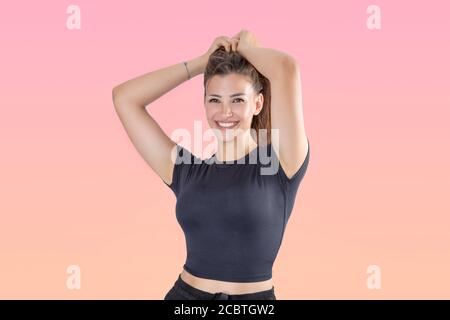 Studio shot of beautiful young woman smiling with hands lifting her long hair Stock Photo