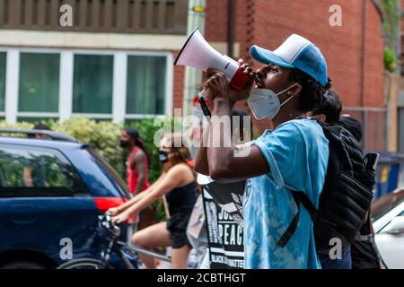 Washington, DC, USA. 15th Aug, 2020. Pictured: One of the leaders of the Defund the Police March uses a megaphone to lead the group in call and response chants through the Columbia Heights neighborhood. Credit: Allison C Bailey/Alamy, 2020.