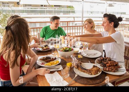 Family Dining and Having Fun Together on the Balcony. Lifestyle Concept of a Family Dinner. No filter Stock Photo