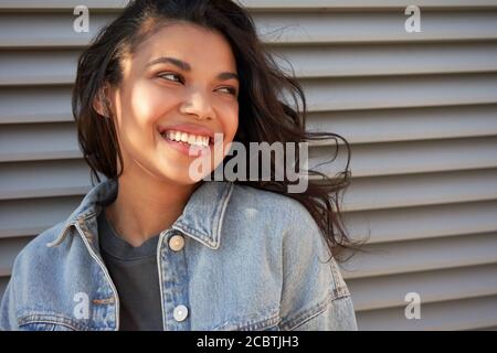Smiling young African American teen girl looking away laughing, headshot.