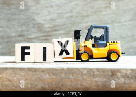 Toy forklift hold letter block x to complete word fix on wood background Stock Photo