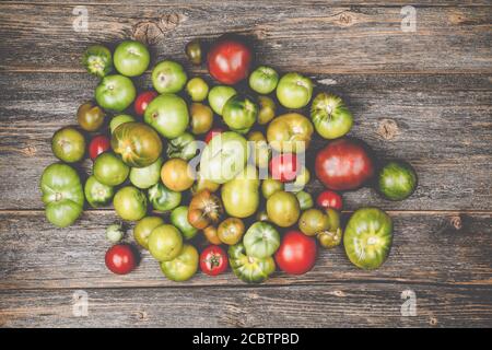 Heap of different sorts of tomatoes on a wooden table Stock Photo