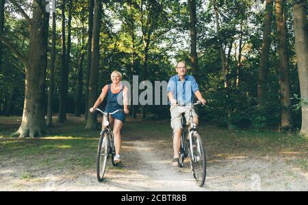 Active seniors riding bike in summer nature. Old people healthy lifestyle and sport concept Stock Photo