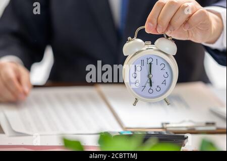 Businessman holding a white alarm clock. Work Time concept. Stock Photo