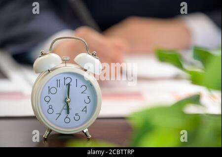 Working Businessman and White Alarm Clock. Work Time concept. Stock Photo
