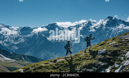 Two young hikers walking up a mountain in Austria, with scenic views on the background Stock Photo
