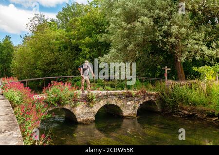 Cyclist on Old Stone bridge on the River Colne at Bilbury, Cotswold, England Stock Photo