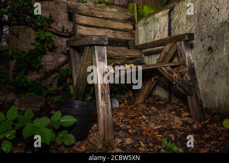Decaying wooden garden chair abandoned in the forgotten corner of the garden Stock Photo