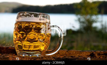 The midnight sun shines on a newly poured beer in a large pint glass. Photo was taken on midsummer's day next to the lake Siljan in Sweden. Stock Photo