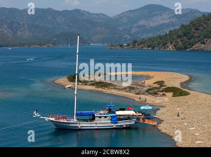 A cruise boat anchored to a small beach in the Mediterranean during the Fethiye Twelve Island cruise off the Turquoise Coast of Turkey. Stock Photo