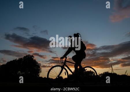 A cyclist rides through a London park at sunset Stock Photo