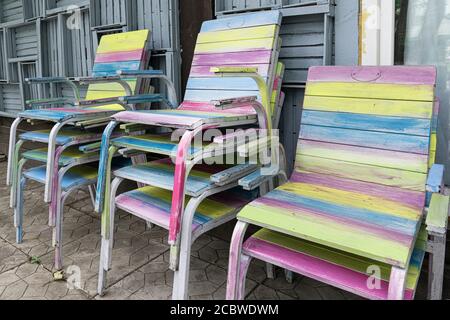 Wooden chairs, hand-painted in different colors, are stacked on the terrace. Stock Photo