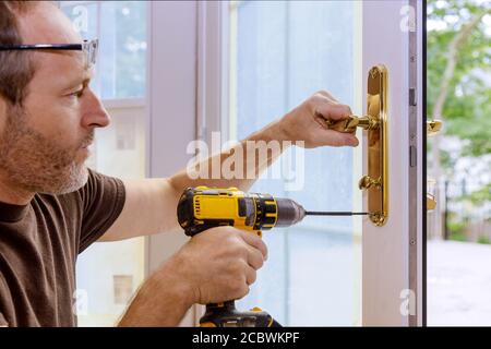 Closeup of a professional locksmith installing or repairing a new deadbolt lock on a house door with the inside internal parts of the lock visible. Stock Photo