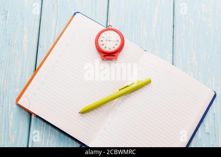 Notepad and stopwatch, on wooden blue background. Stock Photo