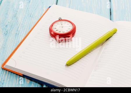 Notepad and stopwatch, on wooden blue background. Stock Photo