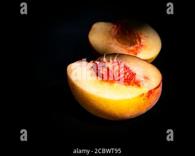 Half peach fruit on a black background. Stock Photo