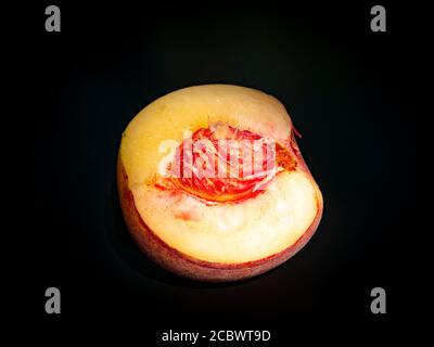 Half peach fruit on a black background. Stock Photo
