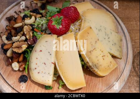 Tasting wooden board with different types of Belgian hard abbey cheeses, nuts and fruits close up Stock Photo