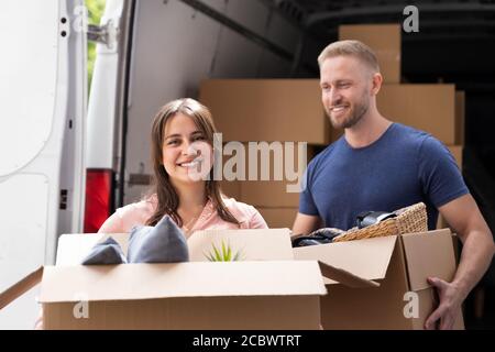 Couple Moving Boxes From Van Or Truck Together Outdoors Stock Photo