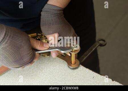 Woman mechanic working in metal workshop using clamps, screws, and spanner Stock Photo