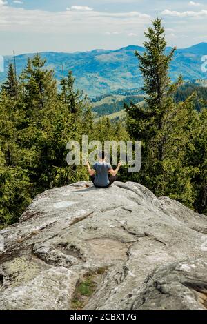 A man is high in the mountains against the sky, celebrating the victory, raising his hands up. Stock Photo