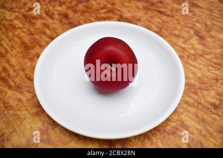 Single plum isolated on white background. Close up of single fruit. purple red maroon cherry plum Stock Photo