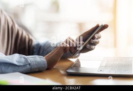 Female hands holding smartphone and using laptop Stock Photo