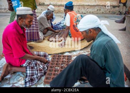 Group of Musilm men playing awale or Bao wearing traditional clothes enjoy leisure time in Lamu island town Stock Photo