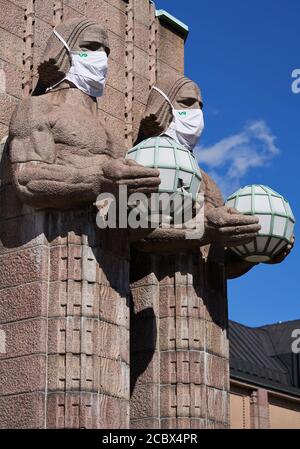 Helsinki, Finland - 16 August 2020: Iconic stone men statues by the side of the entrance to the Helsinki Central Railway Station decorated as wearing Stock Photo