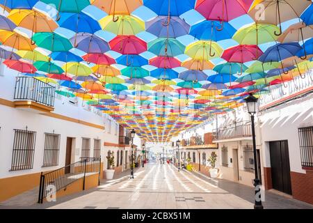 The sky is full of colorful umbrellas. Street with umbrellas in the sky in the village San Bartolome de la torre. Summer decoration and sun  protectio